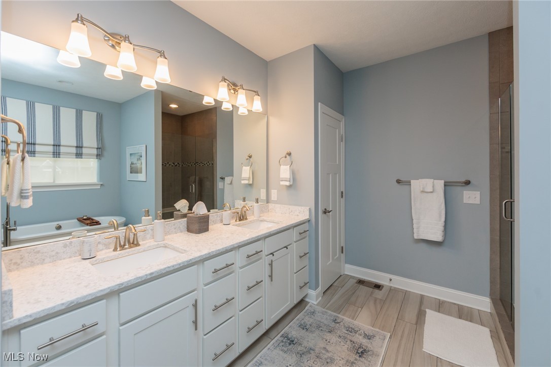 2041 Jaycox Road Avon, OH 44011 - Photo 31 of 50 Full bath featuring a shower stall, double vanity, and light wood-style flooring