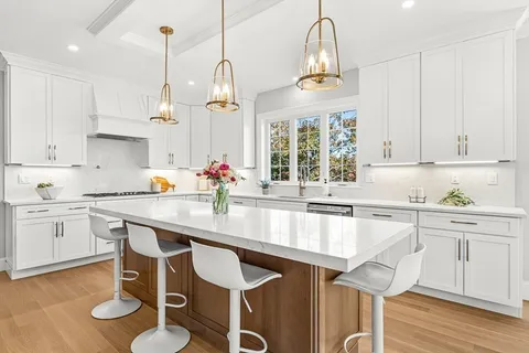 a kitchen with stainless steel appliances granite countertop a sink a stove a dining table and chairs with wooden floor