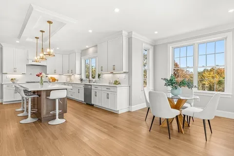 a kitchen with a table chairs wooden floors and a view of living room