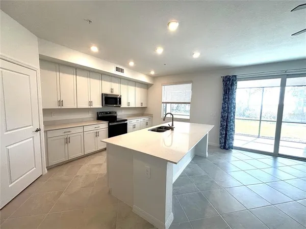 a large kitchen with kitchen island a sink a stove a refrigerator and a cabinets