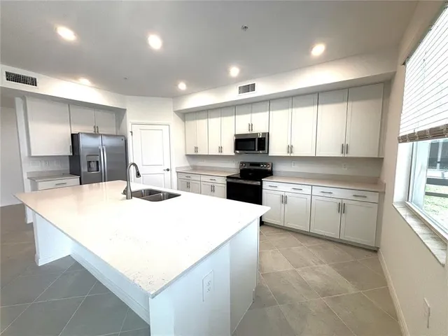 a kitchen with kitchen island white cabinets appliances and window