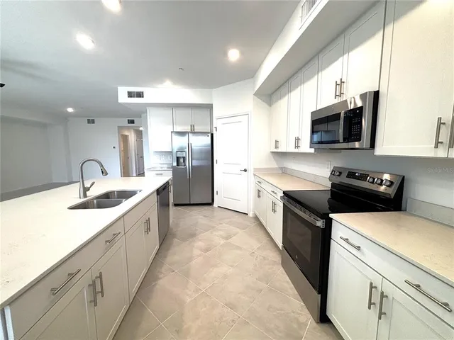 a large kitchen with stainless steel appliances granite countertop a sink a stove top oven and a refrigerator