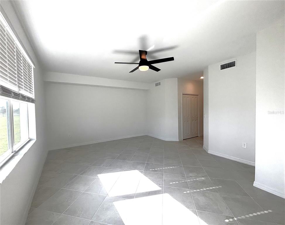 17680 Boracay Court, Unit 101 Venice, FL 34293 - Photo 7 of 42 an empty room with chandelier fan and windows