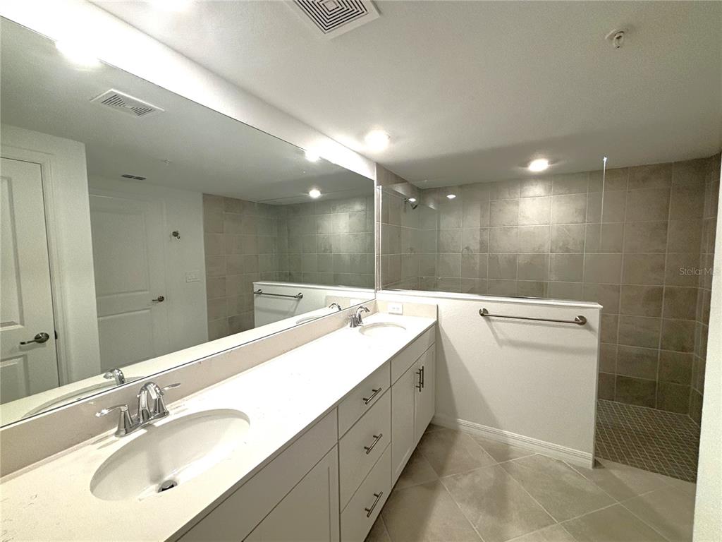 17680 Boracay Court, Unit 101 Venice, FL 34293 - Photo 9 of 42 a bathroom with a double vanity sink a mirror and a