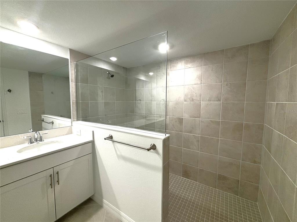 17680 Boracay Court, Unit 101 Venice, FL 34293 - Photo 10 of 42 a bathroom with a shower sink vanity and mirror