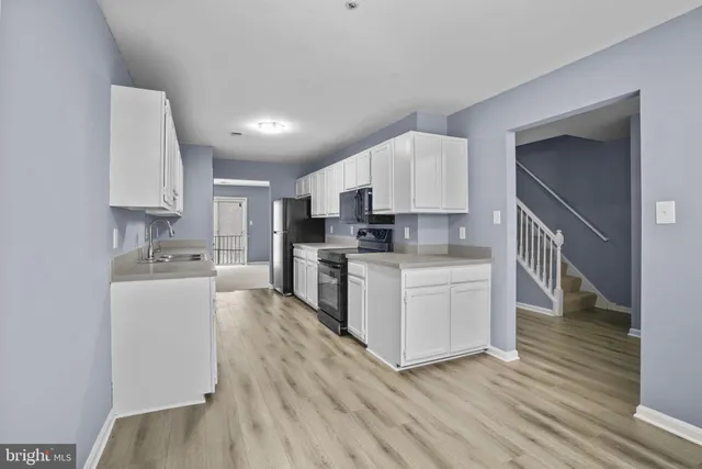 a kitchen with granite countertop a stove top oven a sink dishwasher and a refrigerator with wooden floor