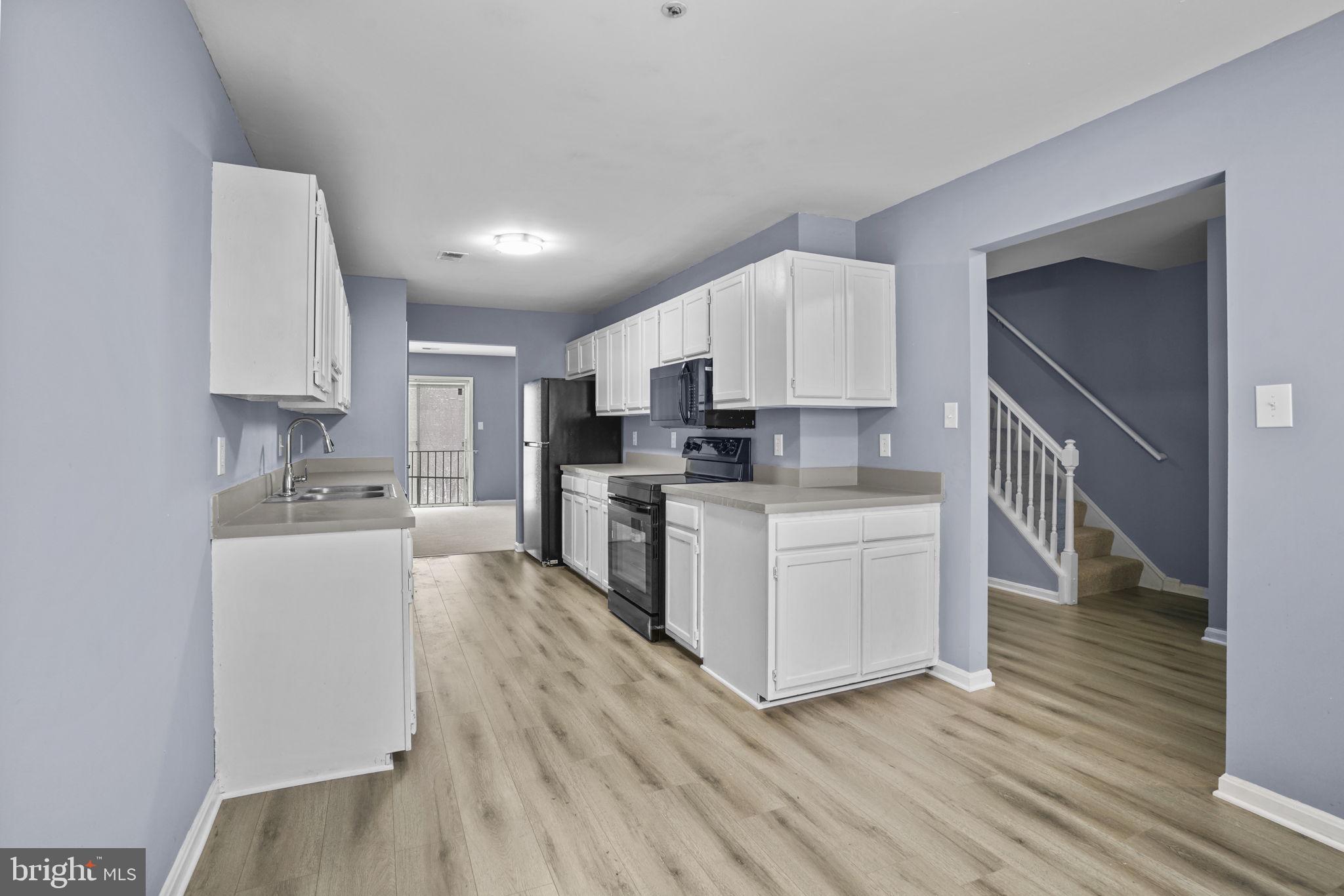 11206 Hannah Way, Unit 4 Upper Marlboro, MD 20774 - Photo 11 of 25 a kitchen with granite countertop a stove top oven a sink dishwasher and a refrigerator with wooden floor