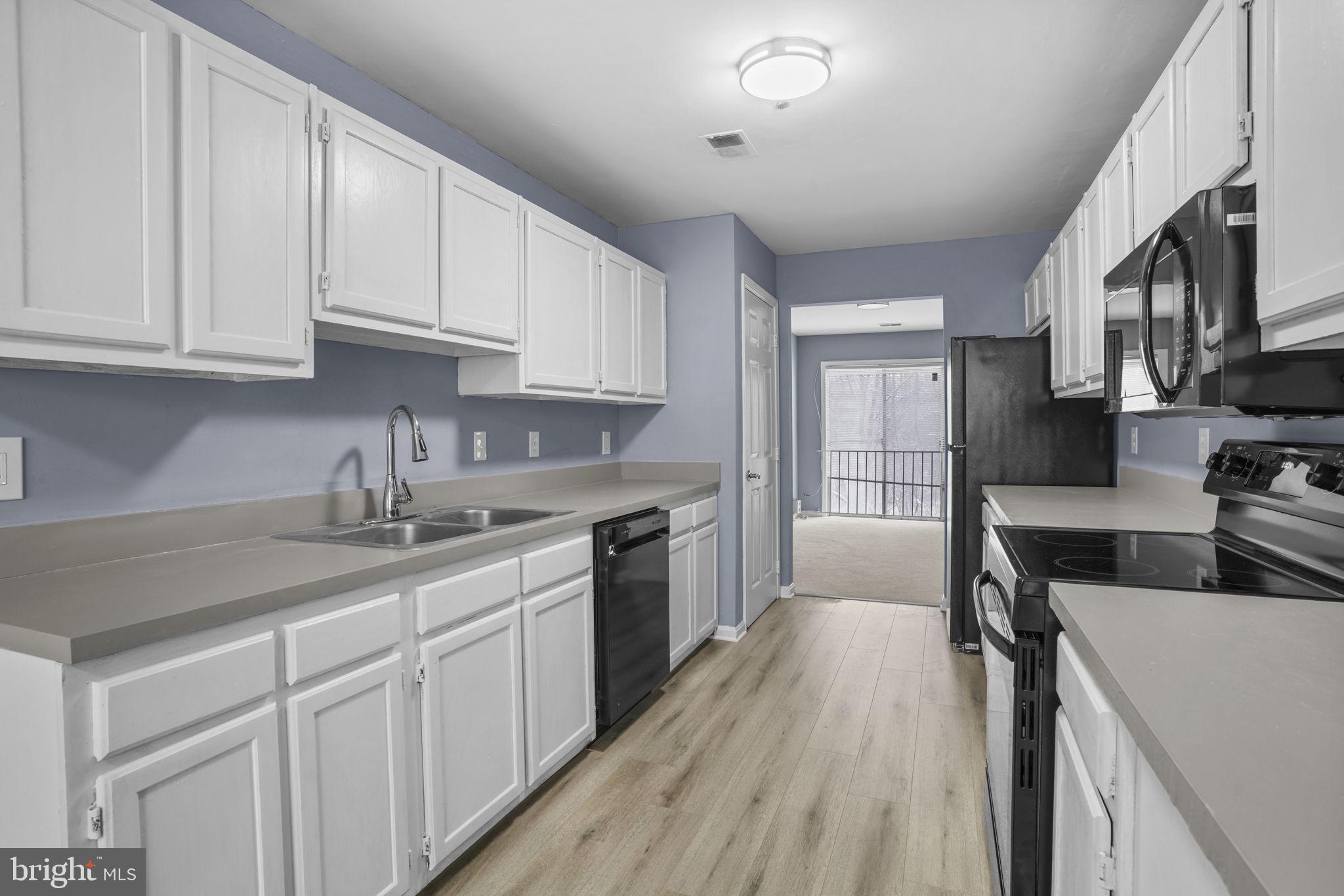 11206 Hannah Way, Unit 4 Upper Marlboro, MD 20774 - Photo 12 of 25 a kitchen with granite countertop a sink dishwasher stove and white cabinets with wooden floor