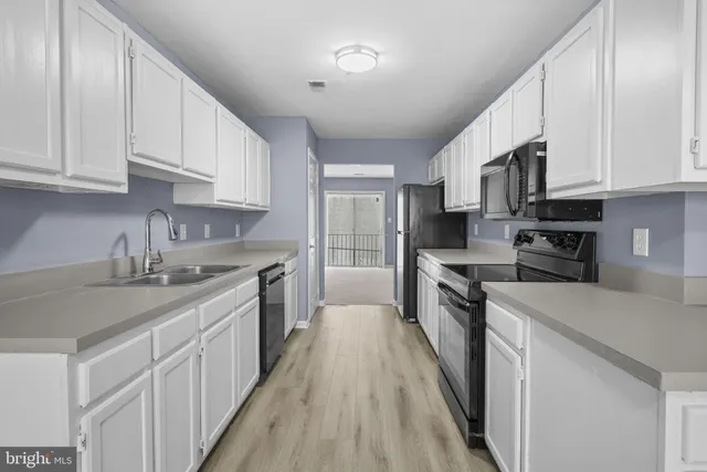 a kitchen with stainless steel appliances granite countertop a stove top oven a sink dishwasher and a refrigerator with wooden cabinets