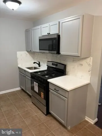 a kitchen with stainless steel appliances a sink a stove a refrigerator a microwave and cabinets