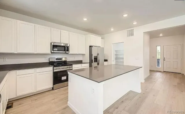an open kitchen with a refrigerator and a stove top oven