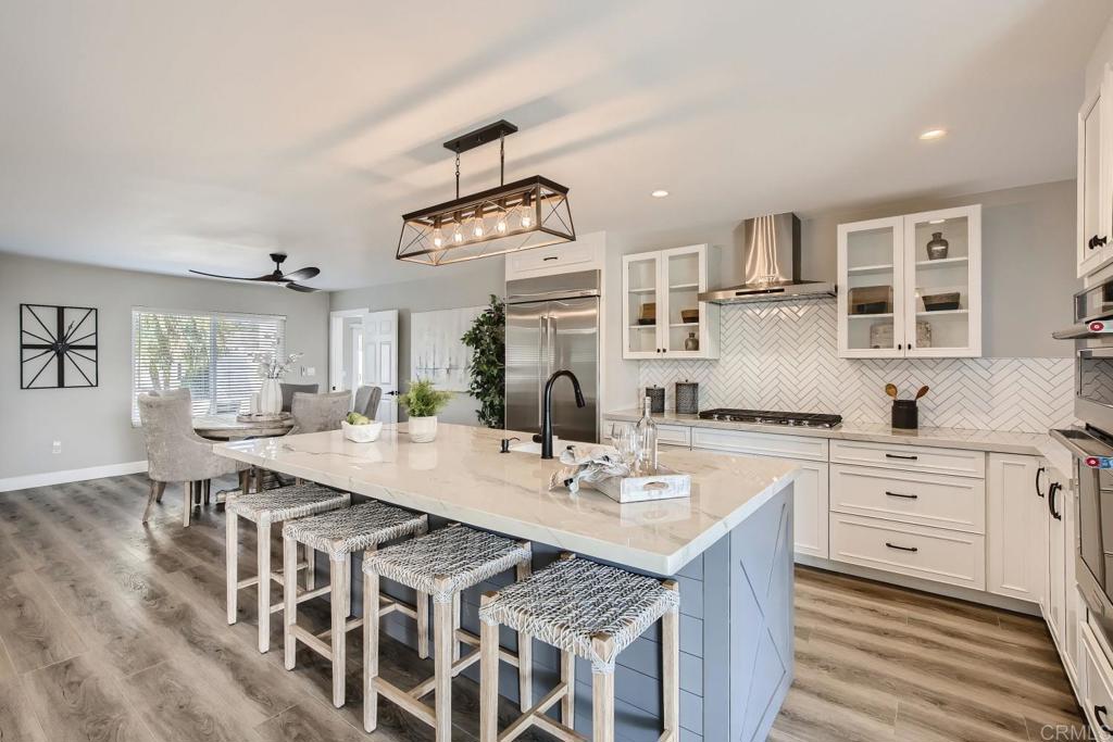 a open kitchen with stainless steel appliances granite countertop a kitchen island a stove a table and chairs in it