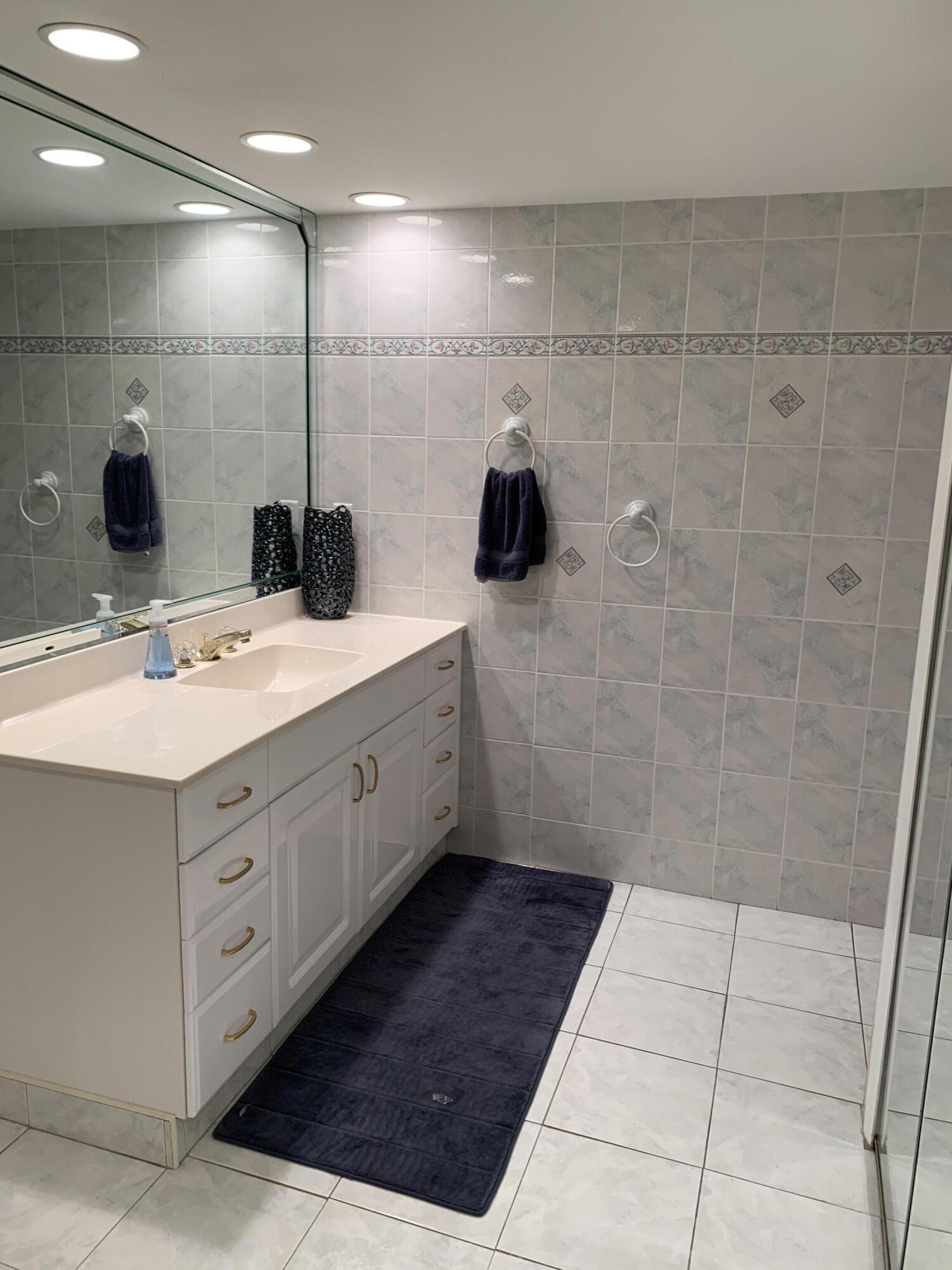 9403 South Ocean Drive, Unit 3D Jensen Beach, FL 34957 - Photo 9 of 15 a bathroom with a double vanity sink a mirror and shower