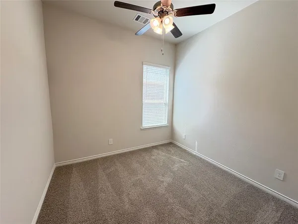 an empty room with a window and a fan