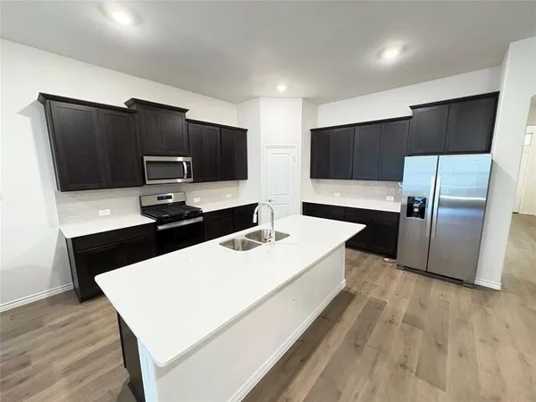 a large white kitchen with a refrigerator and a sink