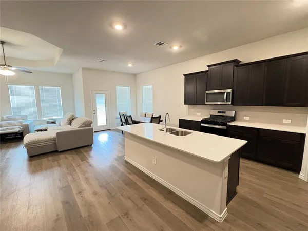 a large room with a lot of counter top space a sink and wooden floor