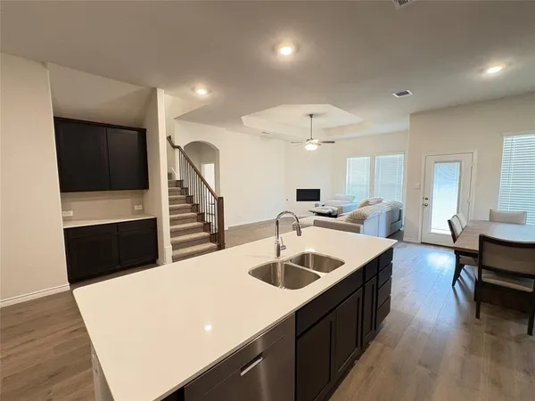 a large white kitchen with a sink a refrigerator and chairs
