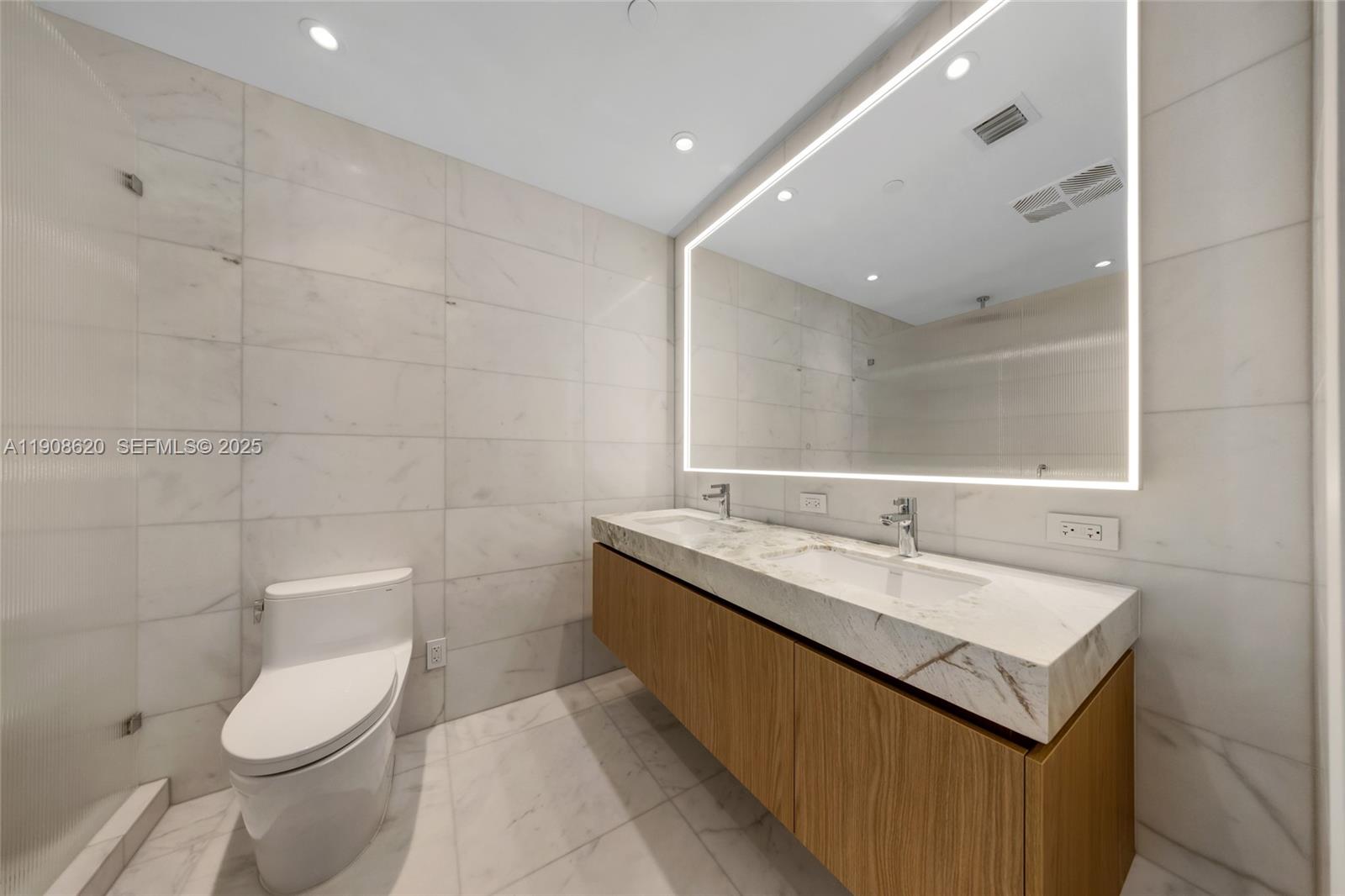 500 Alton Road, Unit 1904 Miami Beach, FL 33139 - Photo 18 of 28 a bathroom with a granite countertop sink a toilet and a mirror