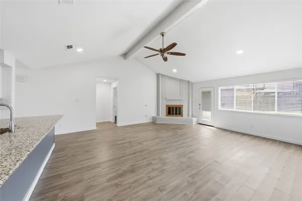 a view of an empty room with window and wooden floor