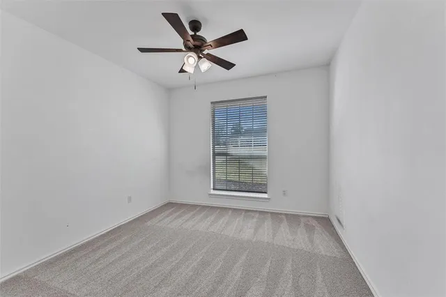 an empty room with wooden floor ceiling fan and windows