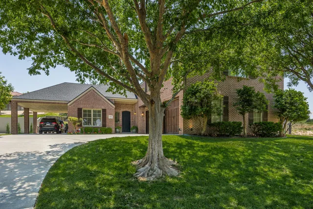 a front view of a house with a yard and trees
