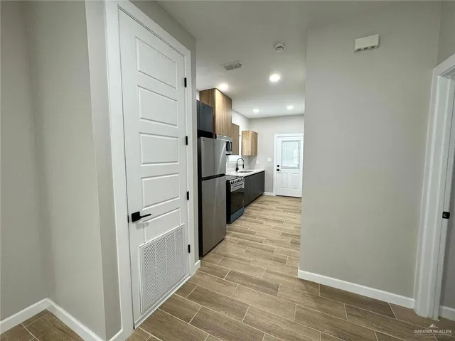 a view of a hallway with stainless steel appliances