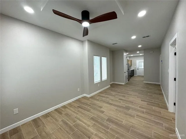 an empty room with wooden floor and windows