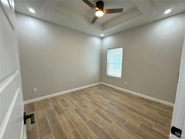 en empty room with wooden floor and fan