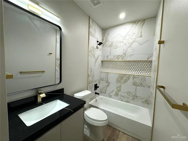 a bathroom with a granite countertop sink toilet and shower