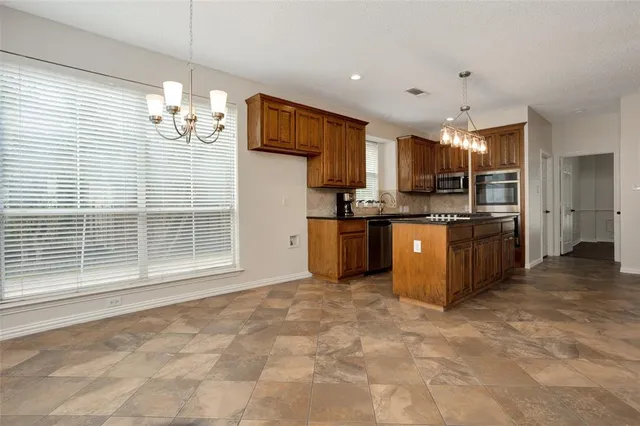 a kitchen with stainless steel appliances kitchen island granite countertop a stove top oven a sink dishwasher a dining table and chairs