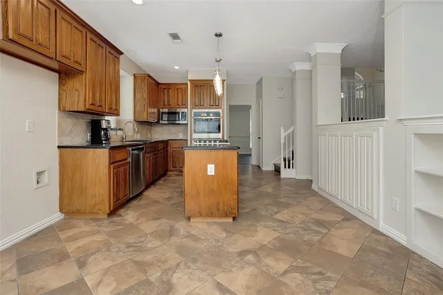 a kitchen with stainless steel appliances granite countertop a refrigerator a stove top oven and a sink