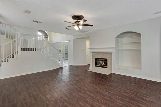 a view of an empty room with wooden floor fireplace and a window