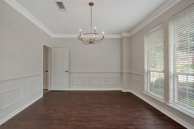 a view of an empty room with wooden floor and windows