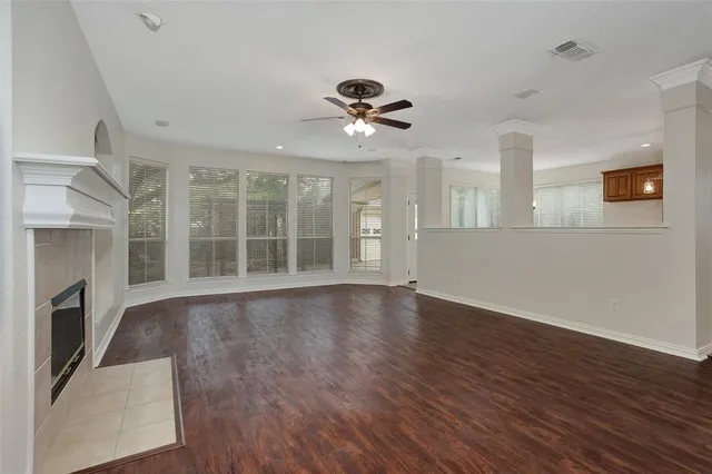 a view of an empty room with wooden floor and a fireplace