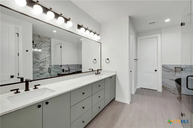 a bathroom with a bathtub shower sink vanity mirror and toilet