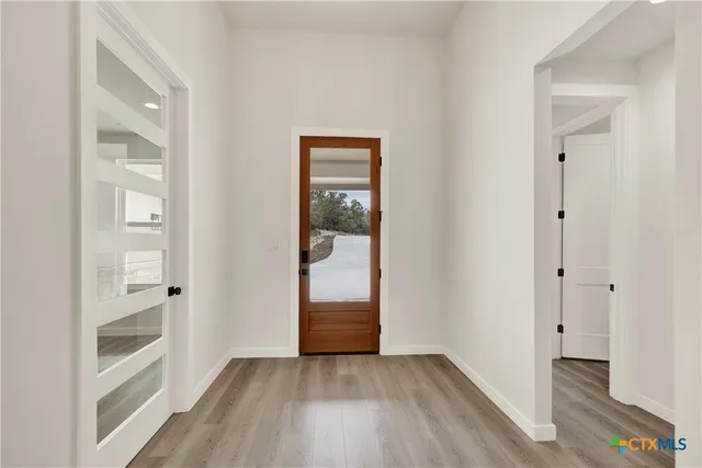 a view of an empty room with a window and wooden floor