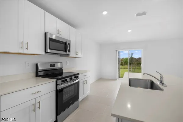 a kitchen with granite countertop a sink a stove top oven and cabinetry