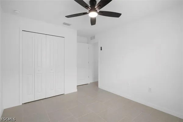 an empty room with closet and a chandelier fan