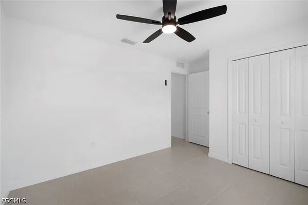 an empty room with a ceiling fan and a window