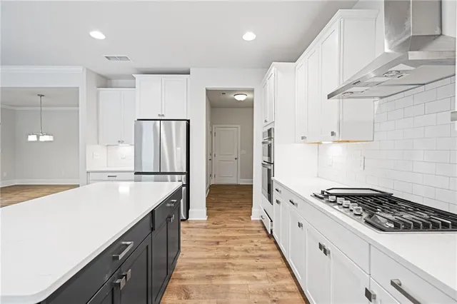 a large kitchen with stainless steel appliances granite countertop a lot of counter space and wooden floors
