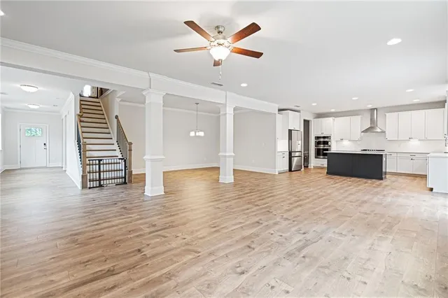 a view of an empty room with wooden floor and a ceiling fan