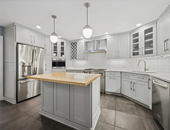 a kitchen with stainless steel appliances granite countertop a sink a stove a refrigerator and island with wooden floor