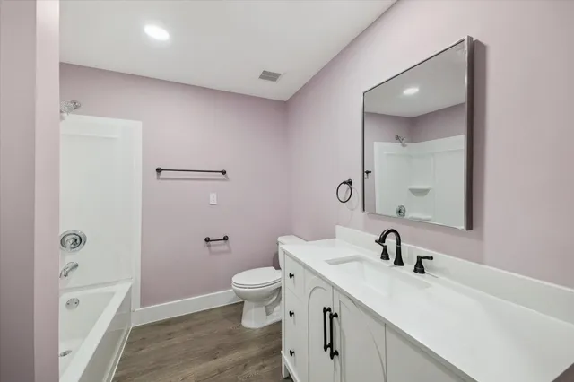 a bathroom with a toilet a sink a mirror a vanity and shower