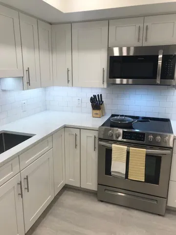 a kitchen with granite countertop white cabinets and black appliances