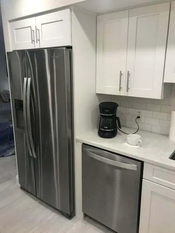 a kitchen with metallic refrigerator and cabinets