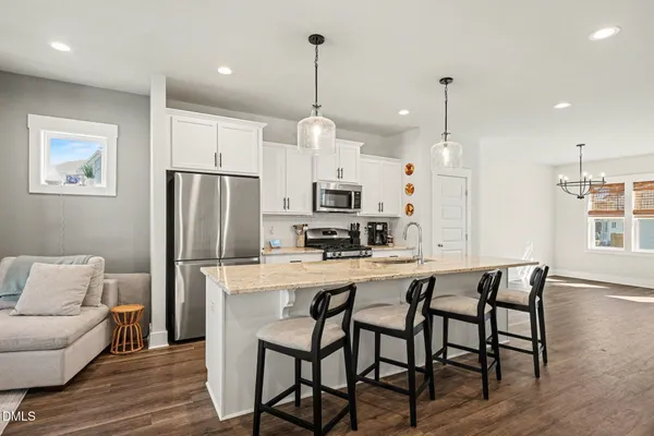 a kitchen with stainless steel appliances a dining table chairs refrigerator and microwave