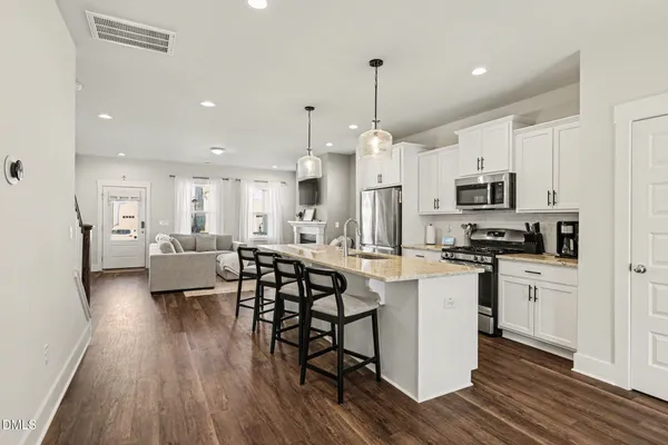a large kitchen with white cabinets stainless steel appliances a dining table and chairs