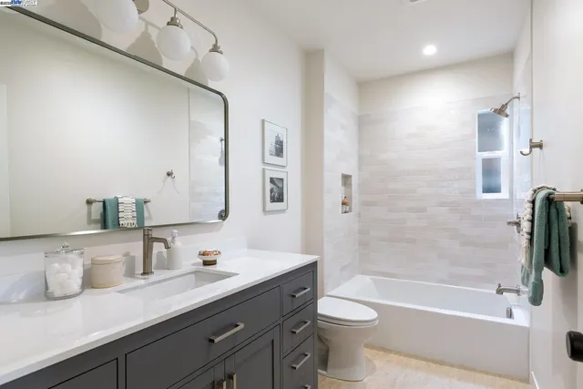 a bathroom with a granite countertop sink a toilet a mirror and shower
