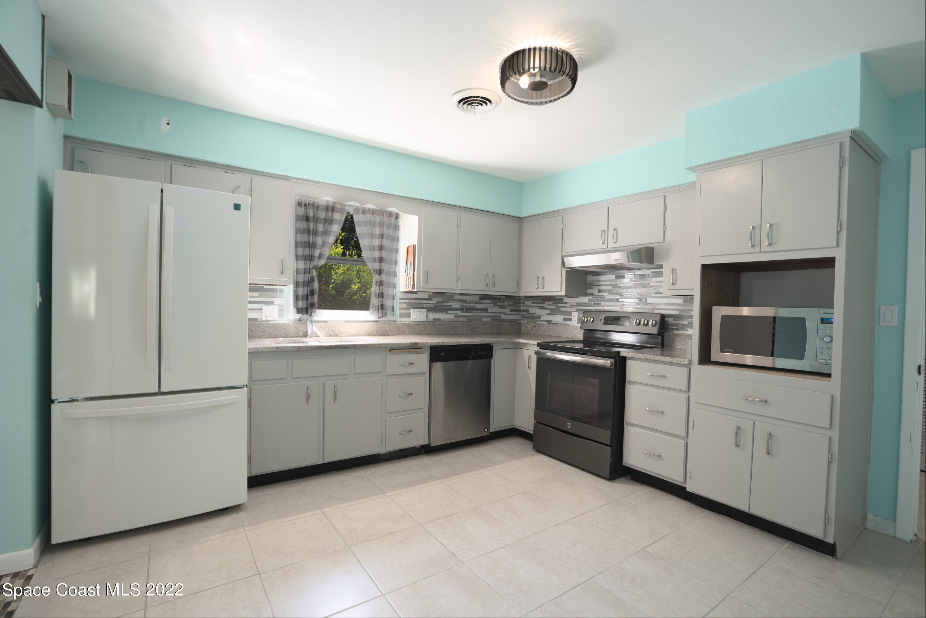 111 Highview Drive Cocoa, FL 32922 - Photo 6 of 17 a kitchen with white cabinets stainless steel appliances and a window