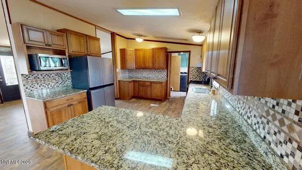 a kitchen with granite countertop a refrigerator a sink and wooden floors